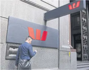  ?? BLOOMBERG ?? A pedestrian uses a smartphone as he walks past a Westpac Banking Corp branch in Sydney.
