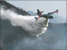  ?? The Associated Press ?? WATER DROP: In this photo provided by the Santa Barbara County Fire Department, a Bombardier 415 Super Scooper makes a water drop on hot spots Sunday morning along the hillside east of Gibraltar Road in Santa Barbara, Calif. One of the largest...