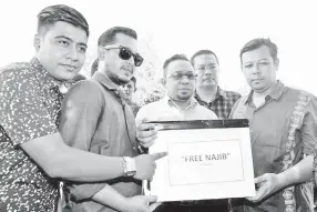  ??  ?? Razlan (right) with Umno supporters of Najib shows a box with the words “Free Najib” for the launch of a donation drive.