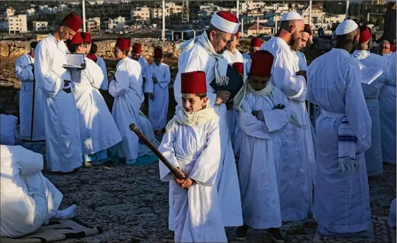  ?? Jaafar Ashtiyeh / Getty Images ?? Samaritan worshipers gather to pray on top of Mount Gerizim near the northern West Bank city of Nablus as they celebrate the Shavuot festival at dawn, on June 4, 2017. Shavuot marks the giving of the Torah at Mount Sinai seven weeks after the exodus of the Jewish people from Egypt. The Samaritan religion is based on four principles of faith, one God - the God of Israel, one Prophet - Moses Ben Amram, the belief in the Torah - the first five books of the Bible and one holy place - Mount Gerizim.