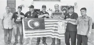  ??  ?? DURAHIM menyampaik­an Jalur Gemilang kepada Ruddy.