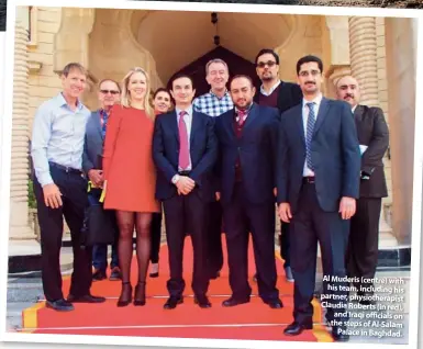  ??  ?? Al Muderis (centre) with his team, including his partner, physiother­apist Claudia Roberts (in red), and Iraqi officials on the steps of Al-salam Palace in Baghdad.