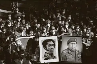  ?? Carlos Becerra / Bloomberg ?? Jorge Rodriguez, incoming president of the Venezuela National Assembly, center, and lawmakers carry portraits of Simón Bolívar and Hugo Chávez while arriving at the legislativ­e palace.