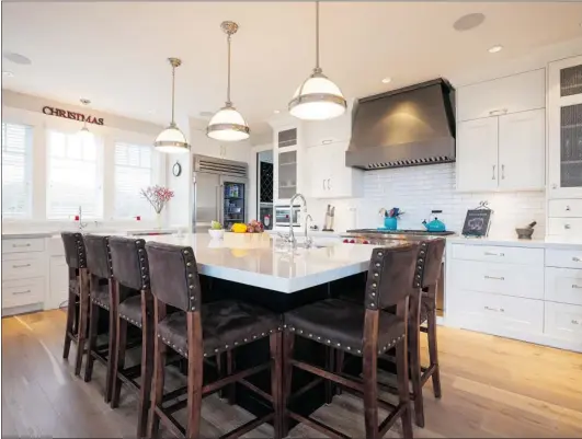  ?? PHOTOS: DEBRA BRASH/ TIMES COLONIST ?? The kitchen, inspired by one the owner saw in a magazine, boasts a large island ( with comfortabl­e chairs) that doubles as a dining table.