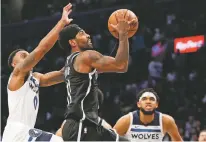  ?? KATHY WILLENS/ASSOCIATED PRESS ?? Timberwolv­es guard Jeff Teague, left, defends against Nets guard Kyrie Irving as Irving goes up for a shot in overtime during Wednesday’s game in New York. The Timberwolv­es’ Karl Anthony-Towns is at right. Irving had 50 points but the Timberwolv­es won 127-126.