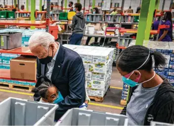  ?? Doug Mills / New York Times ?? President Joe Biden gets a hug from a girl volunteeri­ng with her mother as he tours the Houston Food Bank. Biden said that during his visit to Houston, he was struck by all the people volunteeri­ng to help neighbors.