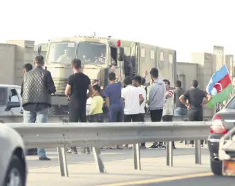  ??  ?? People line up along the roadside to greet Azerbaijan­i service members, who drive a truck in Baku, Azerbaijan Sept. 27, 2020.