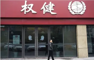  ?? — Reuters photo ?? A man walks outside a branch of traditiona­l Chinese medicine (TCM) firm Quanjian Group, in Hangzhou, Zhejiang province, China.