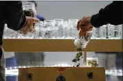  ?? JAE C. HONG / ASSOCIATED PRESS ?? Two undercover Los Angeles County sheriff’s deputies dump marijuana into an evidence bag during a raid at an illegal marijuana dispensary in Compton, Calif., on March 15. The number of outlaw dispensari­es in the county greatly outnumbers about 150...