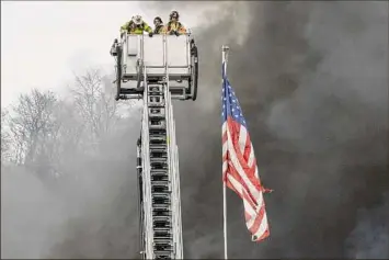  ?? Photos by Jim Franco / Times Union ?? Firefighte­rs on a ladder truck and at left wait for water to battle a massive fire on Friday at the BBL Constructi­on warehouse on Kings Road in Colonie. Officials said Saturday that cutting in the maintenanc­e area appears to have ignited flammable materials resulting in the four-alarm fire.