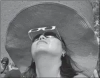  ?? The Associated Press ?? LOOKING UP: Ann Kim Tenhor, of Arlington, Mass., uses protective eclipse glasses to view a partial solar eclipse Monday on the campus of Massachuse­tts Institute of Technology, in Cambridge, Mass.