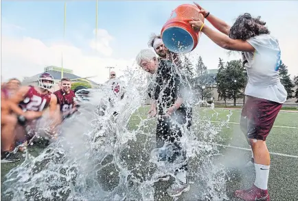  ??  ?? A good-natured Eleanor Gow takes one for the team as Marauders Blaise Barber, left, and Adam Preocanin shower her with water. Eleanor Gow is 76 and she has a perfect 15-0 record coaching the McMaster football team.