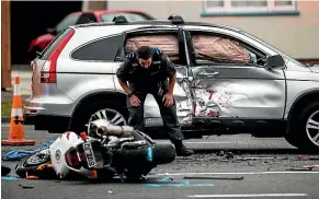  ?? PHOTOS: DAVID UNWIN/STUFF ?? An officer studies the tangled metal of a motorbike that collided with a car in Palmerston North.