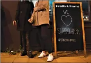  ?? AP Photo / Alberto Pezzali ?? People smoke cigarettes next to a sign outside a bar after a man with a fake bomb strapped to his body stabbed two people in a “terrorism-related” attack on a London street Sunday before he was shot to death by police, authoritie­s said.