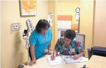  ?? STEVE SINOVIC/JOURNAL ?? Resident aides Bella Sanchez, left, and Lidia Norman go over the daily schedule for assisted living residents at The Neigborhoo­d.