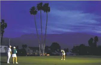  ?? Robert Laberge / Getty Images ?? Pernilla Lindberg makes a putt on the 18th green and fourth extra hole, with Inbee Park and her caddie watching. The golfers played until 15 minutes after sunset in Riverside County.