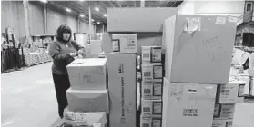  ??  ?? TSA spokeswoma­n Lisa Farbstein stands near boxes of items surrendere­d at BWI checkpoint­s. The items are cataloged and kept at a nearby warehouse.