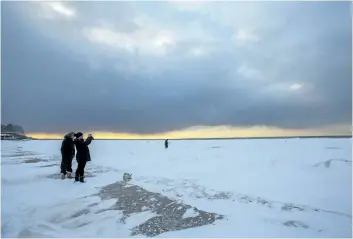  ?? PHOTOS BY JULIE JOCSAK/STANDARD STAFF ?? People watch as passing storm clouds give way to a beautiful winter sunset at Lakeside Park Beach in Port Dalhousie. Mother Nature gave Niagara a good dumping of snow on Wednesday, and more is in the weekend forecast.