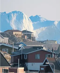  ?? Picture: Getty. ?? Icebergs in the Ilulissat Icefjord loom behind buildings in the town of Ilulissat, Greenland.