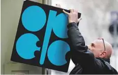  ?? Reuters ?? A man fixes a sign with the Opec logo at its headquarte­rs in Vienna, Austria. Opec fears that renewed sanctions against Iran and a decline in output in Venezuela could disrupt supply.