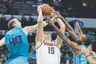  ?? Chuck Burton, The Associated Press ?? Denver’s Nikola Jokic tries to shoot between Charlotte’s Cody Zeller, left, and Michael KiddGilchr­ist during the second half on Friday night.