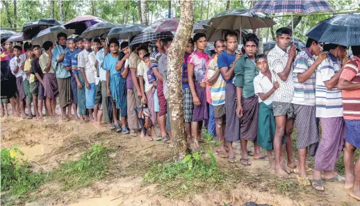  ??  ?? Des Rohingyas attendent pour un sac de riz après avoir traversé la fontière du Bangladesh, au camp de réfugié de Balukhali, dimanche. − Associated Press: Dar Yasin