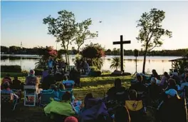  ?? PATRICK CONNOLLY/ORLANDO SENTINEL ?? People gather at sunrise for a church service during an Easter Eat, Pray, Swim event at Lucky’s Lake Swim in Orlando, a longtime tradition.