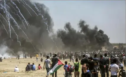  ?? Hosam Salem/The New York Times ?? Tear gas canisters fall near protesters May 14 along the Gaza border with Israel. A mass attempt by Palestinia­ns to cross the border fence separating Israel from Gaza turned violent.