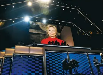  ?? Drew Angerer Getty Images ?? HILLARY CLINTON speaks on the big screen above digital video boards with a symbolic wicker-like design.