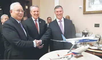  ??  ?? Prime Minister Najib shakes hands with McAllister (right) at the Memorandum of Understand­ing Exchange Ceremony between Boeing and MAB, while Bellew (centre) looks on. Boeing and MAB signed a memorandum of understand­ing to acquire 16 airplanes - eight...