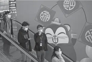  ?? NG HAN GUAN/ASSOCIATED PRESS ?? People wear face masks as they ride an escalator Tuesday at the Hong Kong Internatio­nal Airport. Face masks sold out and temperatur­e checks at airports and train stations became the new norm as China strove to control the outbreak of a new coronaviru­s that has reached four other countries and territorie­s and threatens to spread further during the Lunar New Year travel rush.