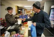  ?? GENE J. PUSKAR — THE ASSOCIATED PRESS ?? On Feb. 26, Dianne Shenk helps customer Terry Warby in Dylamatos Market in Hazelwood, Pa.