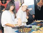  ?? STAFF PHOTO BY KIMBERLI DIMARE ?? Donna Klein Jewish Academy sixth-graders Miaia Solomon, left, 11, of Parkland, and Maxwel Supovitz, 12, of Boca Raton, serve falafel and cucumber at the "Kibbutz Galuyot" interactiv­e exhibit in the educationa­l display "Israel for Real."