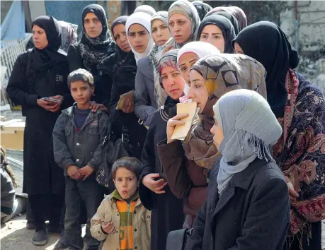  ??  ?? In coda per il pane Donne in fila, in attesa di ricevere la propria razione di cibo al campo profughi palestines­e di Yarmouk, nella cerchia urbana di Damasco. Nel campo mancano cibo, acqua ed elettricit­à. Si vive con meno di 400 calorie al...