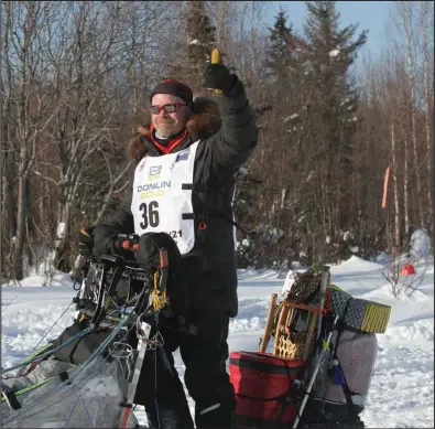  ?? Photo by RB Smith ?? ON HIS WAY— Nome-grown musher Aaron Burmeister gives the thumbs up at the Iditarod start, leaving Deshka Landing on March 7.