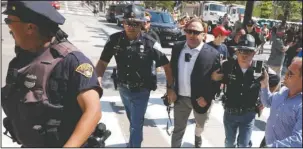  ?? The Associated Press ?? VIOLATING POLICY: In this Tuesday, July 19, 2016 file photo, Alex Jones, center right, is escorted by police out of a crowd of protesters outside the Republican convention in Cleveland. Facebook says it has taken down four pages belonging to conspiracy theorist Alex Jones for violating its hate speech and bullying policies. The social media giant said in a statement Monday that it also blocked Jones’ account for 30 days because he repeatedly posted content that broke its rules.