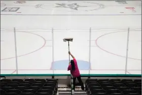  ??  ?? A worker cleans the safety glass at American Airlines Arena in Dallas. The NHL announced Thursday that it is suspending its season indefinite­ly in response to the coronaviru­s.
(The Dallas Morning News/AP/Ashley Landis)