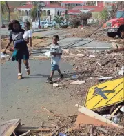  ??  ?? ABOVE: A woman with her two children walks past debris left by Hurricane Irma in Charlotte Amalie, St. Thomas, U.S. Virgin Islands. The storm ravaged such lush resort islands as St. Martin, St. Barts, St. Thomas, Barbuda and Anguilla.