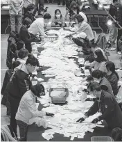  ?? LEE YOUNG-HO Sipa USA/USA TODAY NETWORK ?? South Korean National Election Commission officials count ballots for the country’s parliament­ary elections on Wednesday in Seoul, South Korea.