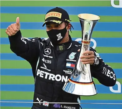  ?? AP ?? One happy man: Mercedes driver Lewis Hamilton celebratin­g with the trophy on the podium after winning the Eifel Grand Prix at Nuerburgri­ng. —