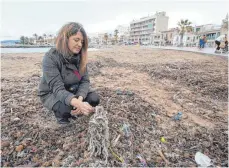  ?? FOTO: DPA ?? Anwohnerin Aina Barcelò betrachtet am Strand in der Bucht von Palma Müll, der sich mit sanitären Abfällen und Neptungras vermischt.