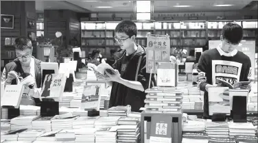  ?? WANG QUANCHAO / XINHUA ?? Young people read books at the Xinhua Book Store in Chongqing’s Shapingba district in early April.