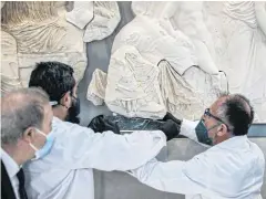  ?? AFP ?? Acropolis Museum staff display a fragment from the Parthenon, believed to depict the foot and lower tunic of the goddess Artemis, in Athens on Monday.