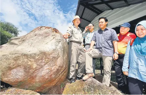  ??  ?? Dr Abdul Rahman (centre) and others looking at the carving on the rock next to the Bongkissam shrine, as pointed out by Leh (left) during a visit to the Santubong historical sites yesterday. — Photo by Mohd Rais Sanusi