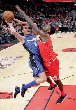  ?? AP ?? Orlando Magic’s Mario Hezonja ( left) shoots the ball as Bobby Portis of the Chicago Bulls tries to defend in the second half of their NBA basketball game on Monday in Chicago. The Bulls won 105- 101. —