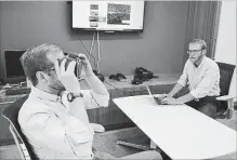  ?? P. SOLOMON BANDA THE ASSOCIATED PRESS ?? Nick Harrell holds up a pair of virtual reality goggles that are used in therapy to treat his fear of flying. Behavioral Health Scientist Sam Hubley is at right.