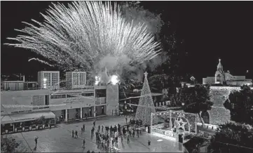  ?? EMMANUEL DUNAND/GETTY-AFP ?? A fireworks display is set off Saturday during the lighting of the Christmas tree in the biblical city of Bethlehem. Only a few dozen people attended the ceremony near the Church of the Nativity, where Christians believe Jesus was born. Others watched it online due to the coronaviru­s pandemic. The annual event normally draws thousands of pilgrims.