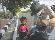  ??  ?? Veena Gupta teaches the English alphabet to a child on a sidewalk in New Delhi.