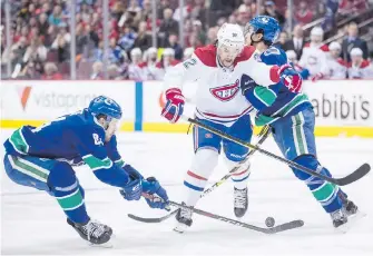  ?? THE CANADIAN PRESS ?? Montreal Canadiens’ Jonathan Drouin is checked by the Canucks’ Michael Del Zotto, right, as Tyler Motte, left, reaches for the puck during first-period action in Vancouver on Saturday.