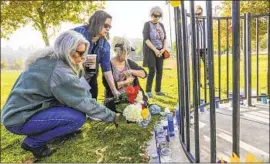  ?? Irfan Khan Los Angeles Times ?? VICKY NELSON, left, Cindy Vincej and Criss Owens place flowers at Central Park in Santa Clarita for the victims of the shooting at Saugus High School.